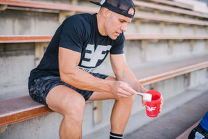 Man sitting on bleachers with a red shaker bottle