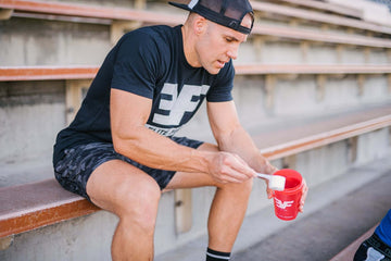 Man sitting on bleachers with a red shaker bottle