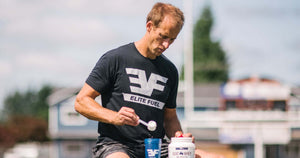 Man with a scoop of protein powder pouring into shaker bottle