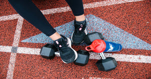 Tennis shoes with water bottle and dumbbells on track