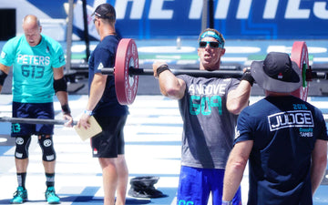 Master's athlete holding a weighted barbell at a CrossFit competition