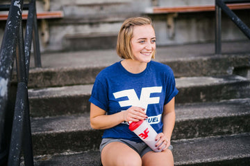 Young woman sitting on stairs holding a shaker bottle