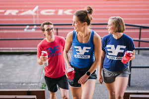 Two women and one man with shaker bottles standing on bleacher stairs
